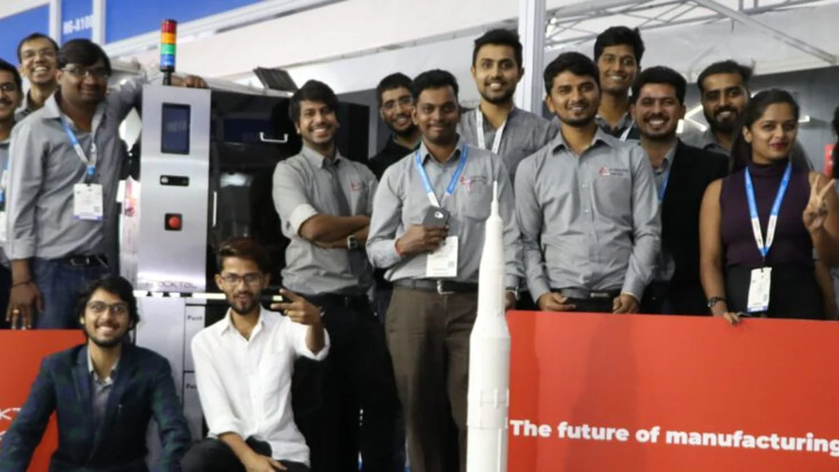 The Fracktal Works team beside a printer and a large 3D printed rocket model