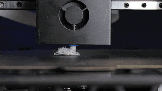 A nozzle extruding filament into a tangled nest above an empty build plate
