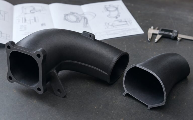 A 3D printed automotive intake prototype on an engineering bench