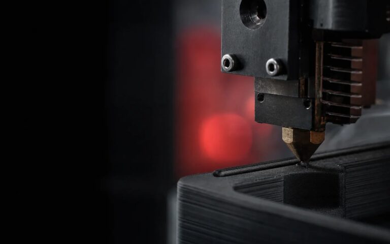 An FDM 3D printer nozzle laying down a layer, close up